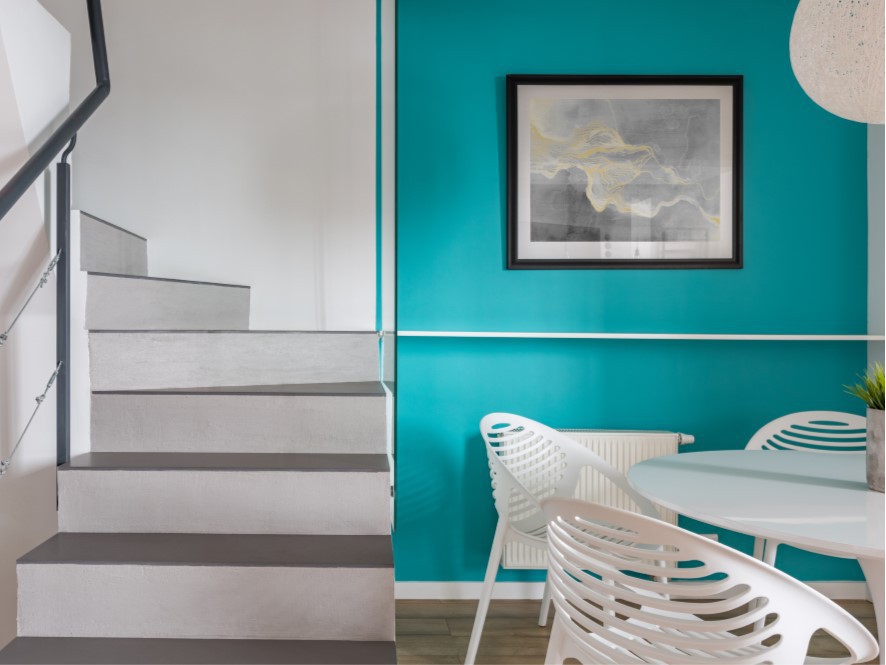 Turquioise_feature_wall_timber floor_white_table_chairs_contrasting_white_stairs_artwork